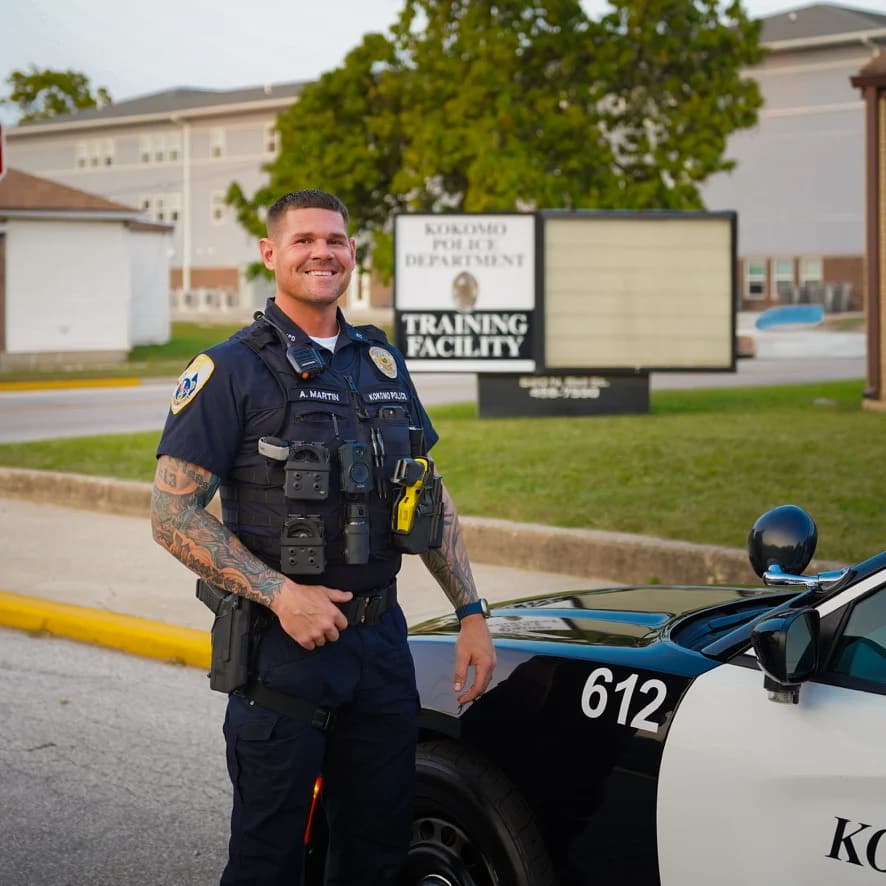Adam Martin, Kokomo police officer and owner of Outdoor Muscle, in uniform beside his patrol car