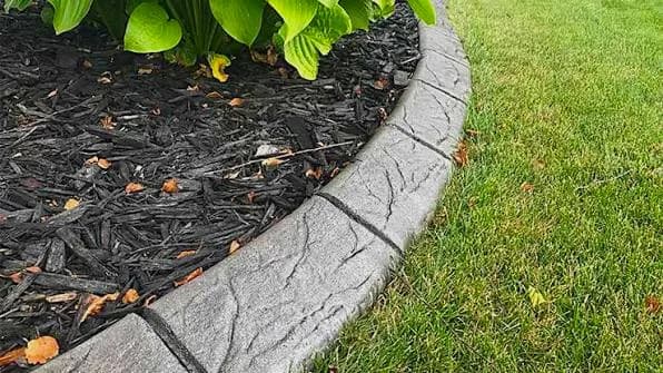 Decorative stamped concrete curbing framing a mulch bed
