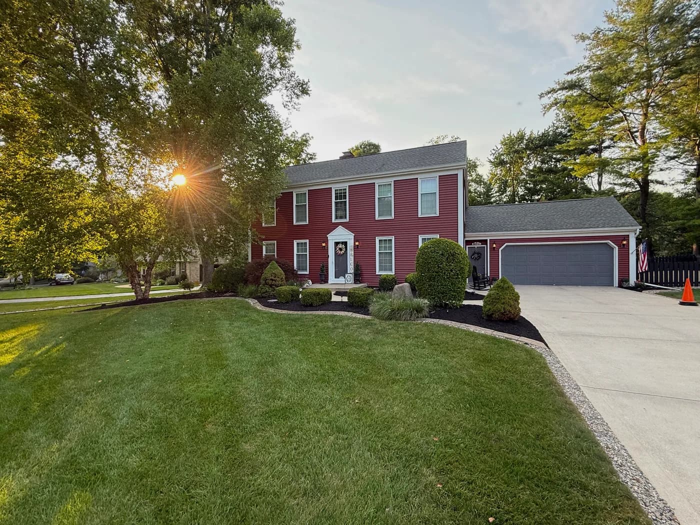 Freshly mowed front lawn and trimmed landscape beds at a red colonial home