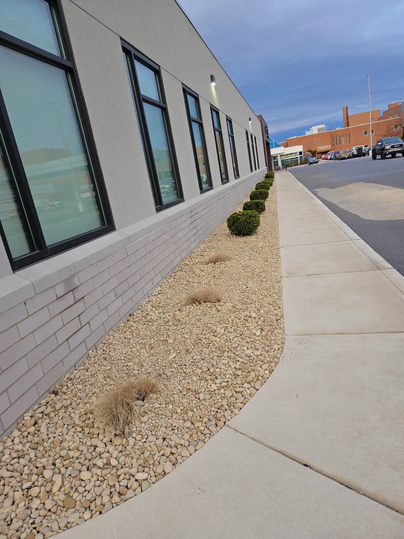 Fresh river-rock bed and crisp sidewalk edging along a commercial building